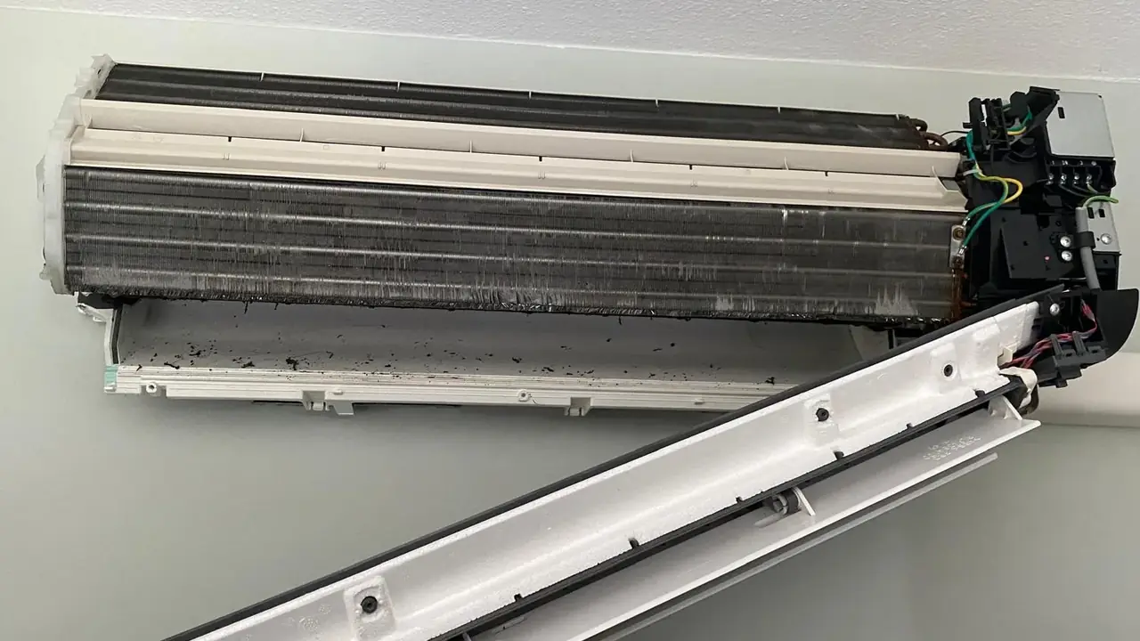 Binnendeel zonder front, met een stoffige verdamper en zwart vuil in de lekbak.