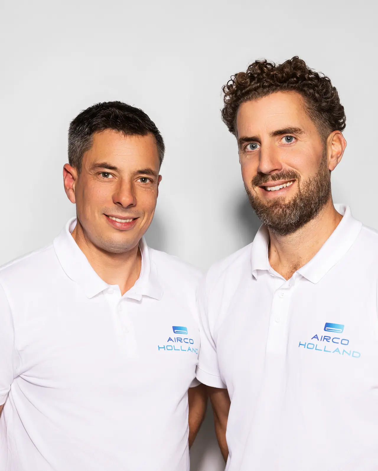 Peter (links) en Rein (rechts) van Airco Holland lachen in de camera, in witte polo's met het logo.