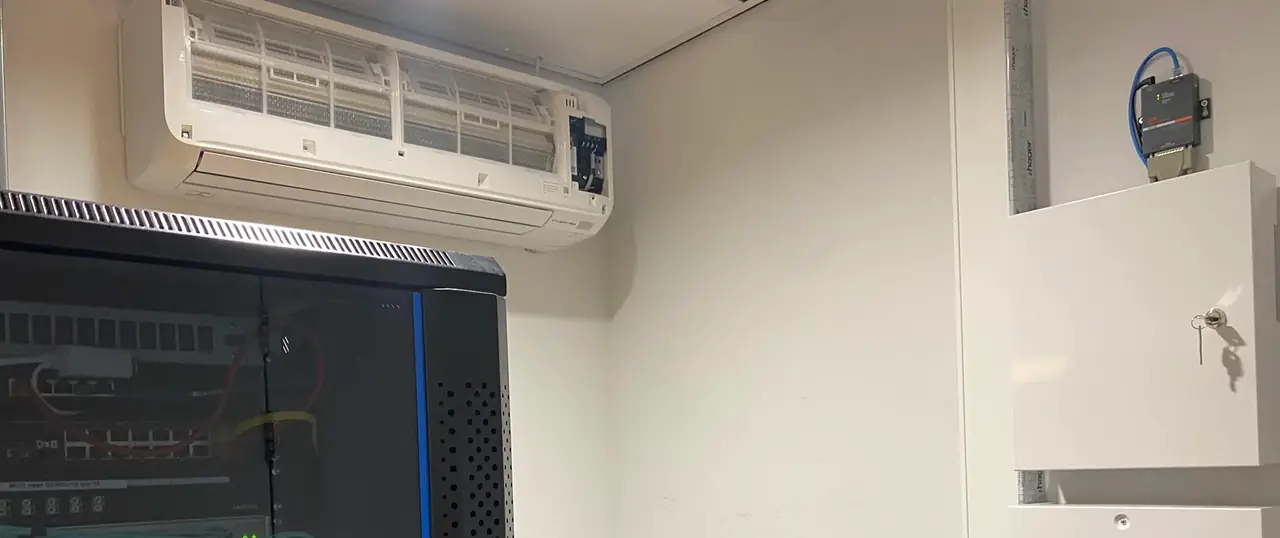 Een wandmodel hangt boven een zwart serverrek in een serverruimte.